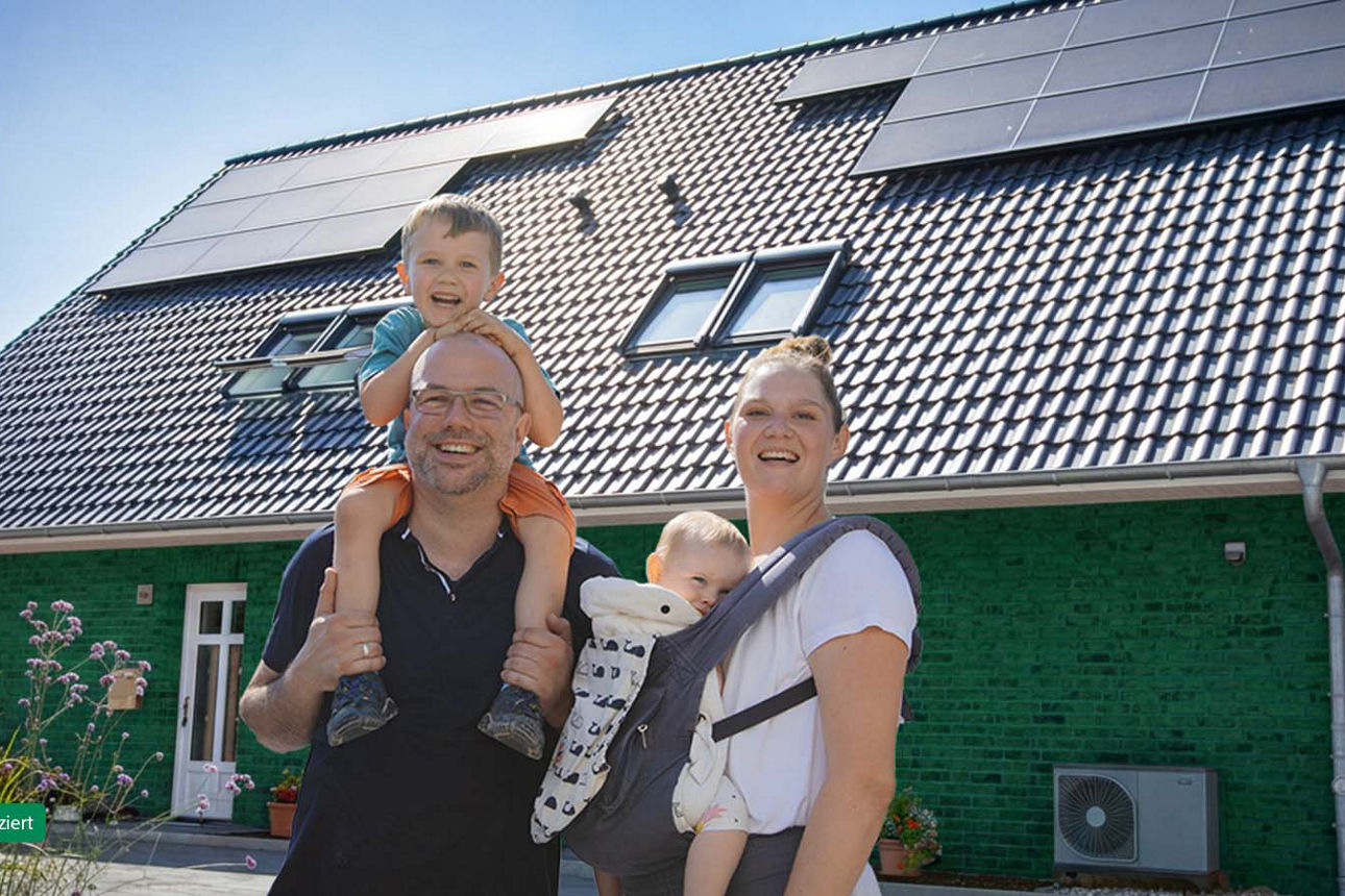Paar mit zwei Kindern steht vor ihrem Eigenheim