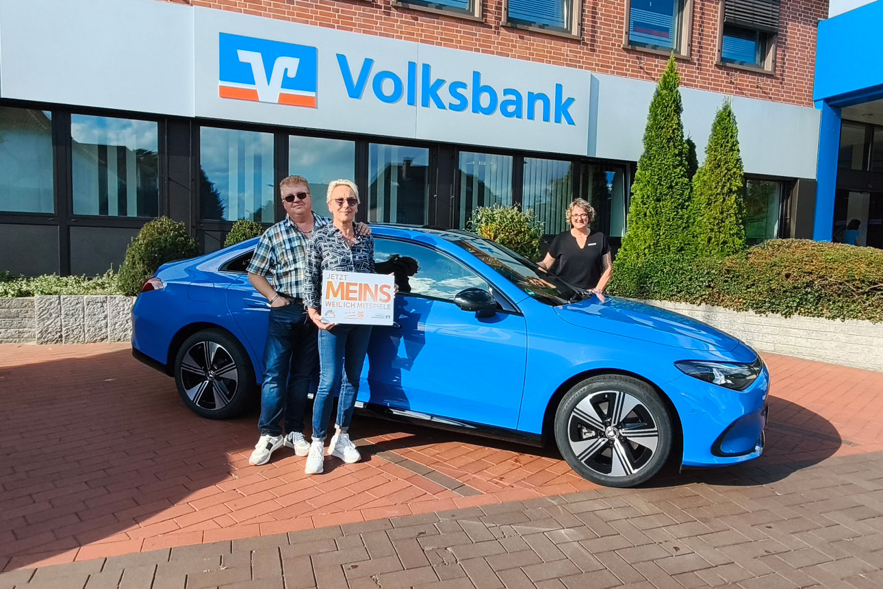 Autogewinner und Geschäftsstellenleiterin präsentieren den neuen Mercedes vor der Volksbank in Harpstedt.