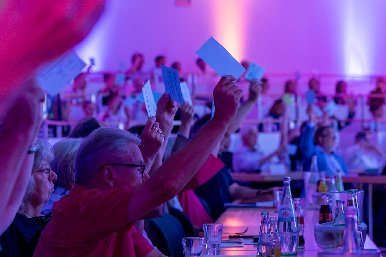 Foto unserer Vertreterversammlung. Das Bild zeigt Menschen im Saal mit Stimmkarten