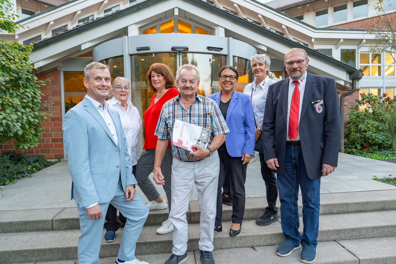 Vor dem Haupthaus der Volksbank im Rheinland steht eine Gruppe von Erwachsenen.