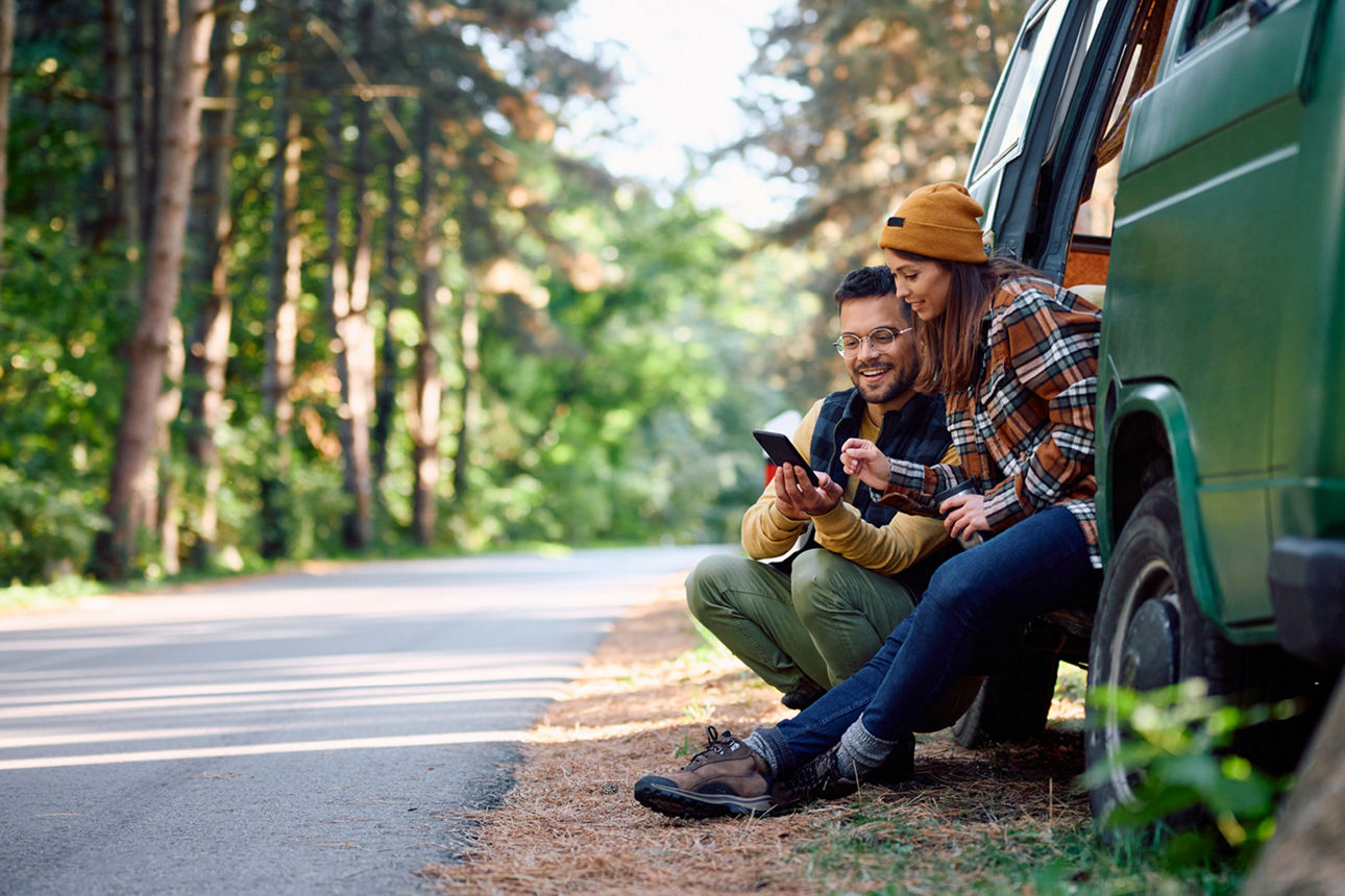Junger Leute mit Van unterwegs sehen aufs Handy.
