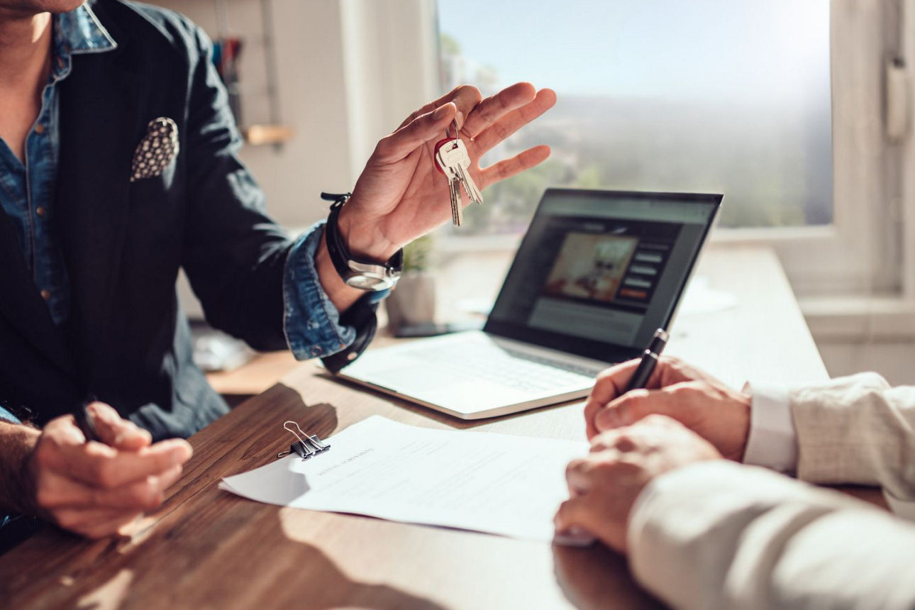 Beraterin übergibt Schlüssel an Kunden.