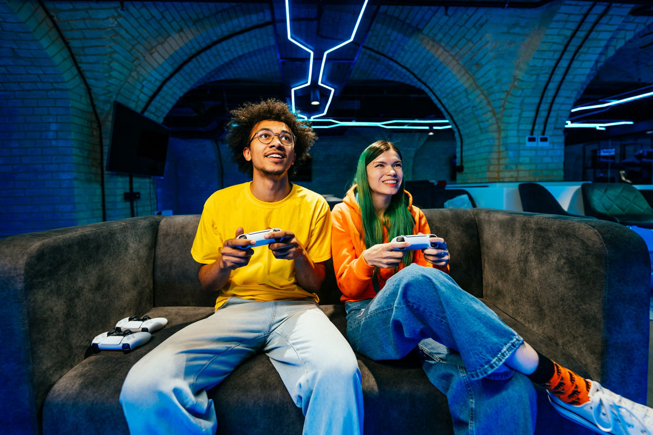 Ein Mann und eine Frau sitzen auf einer Couche und spielen Games auf der Konsole