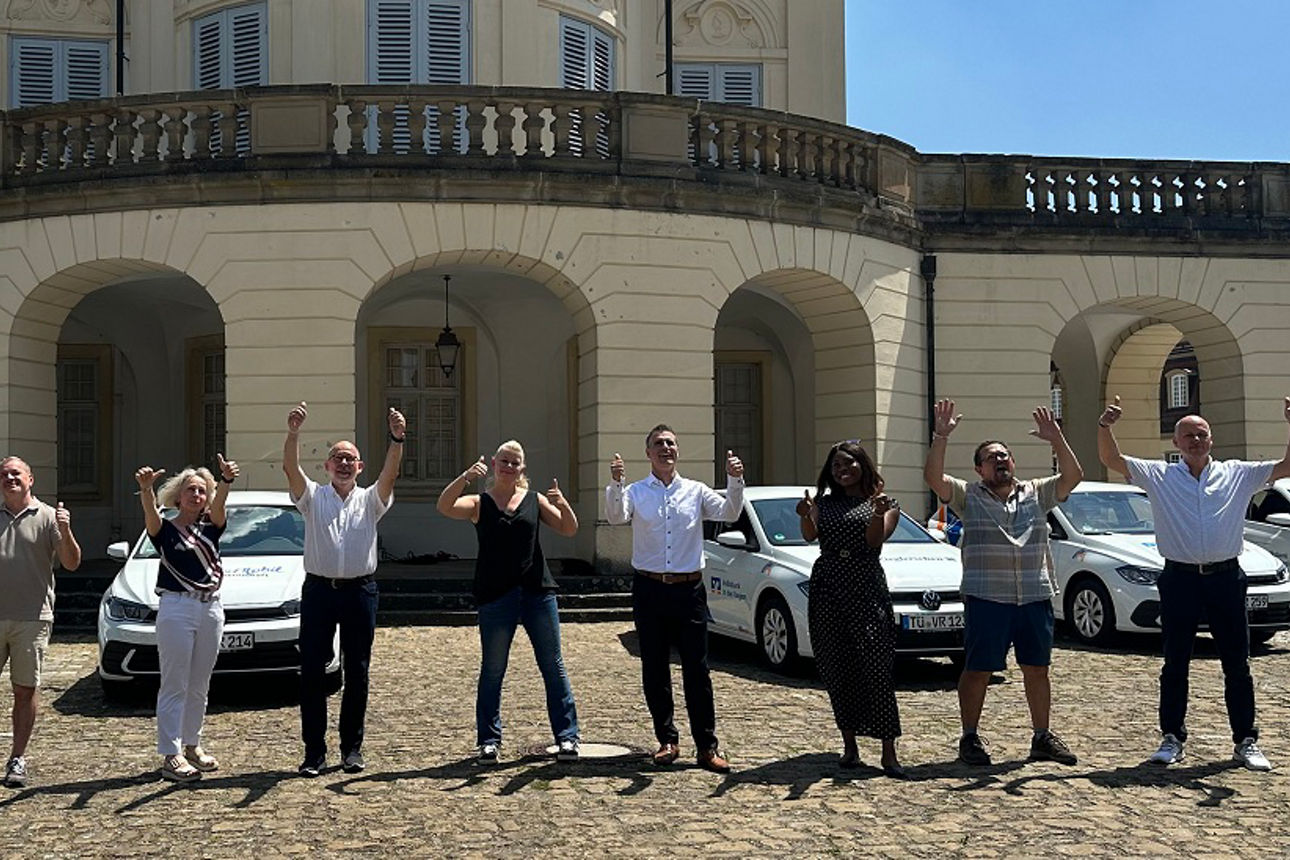 Jubelnde Menschen stehen vor VRmobil vor Schloss Solitude