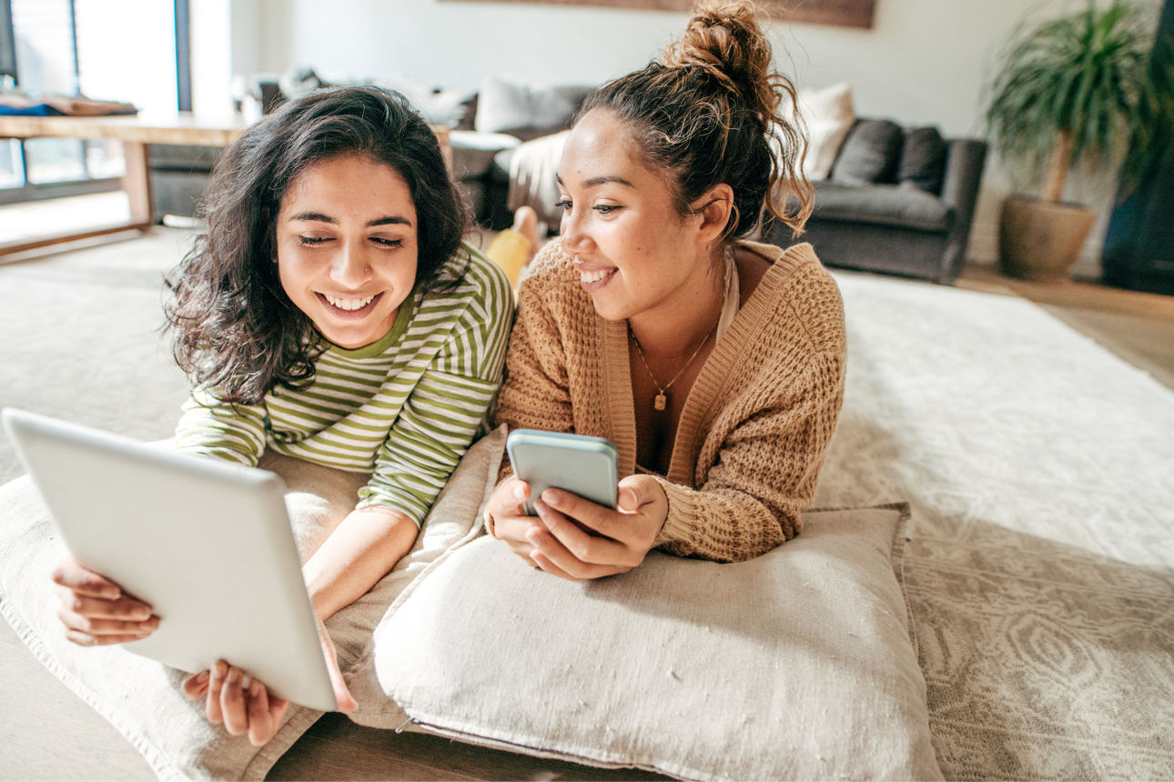 Two female students with digital tablet and cellphone at home