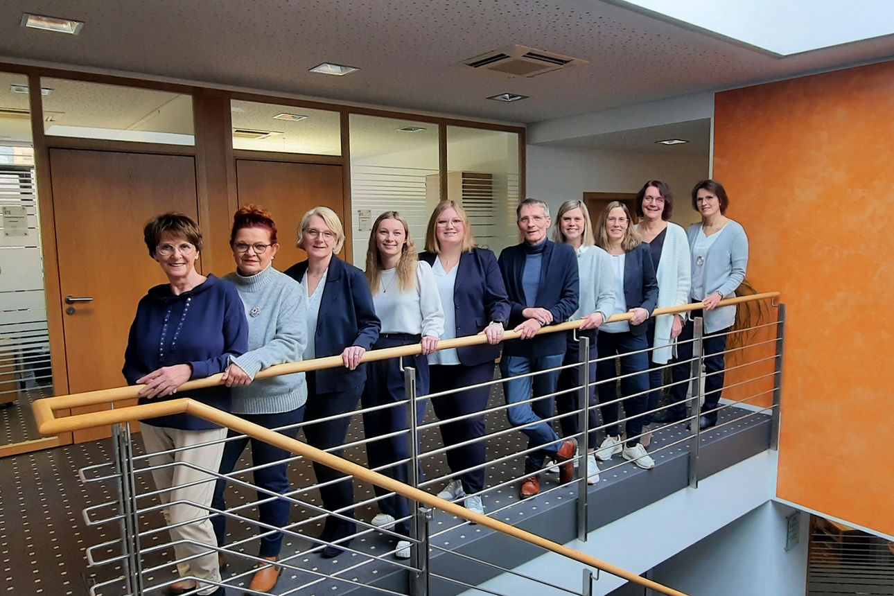 Eine Gruppe von zehn Personen steht vor einem Geländer.