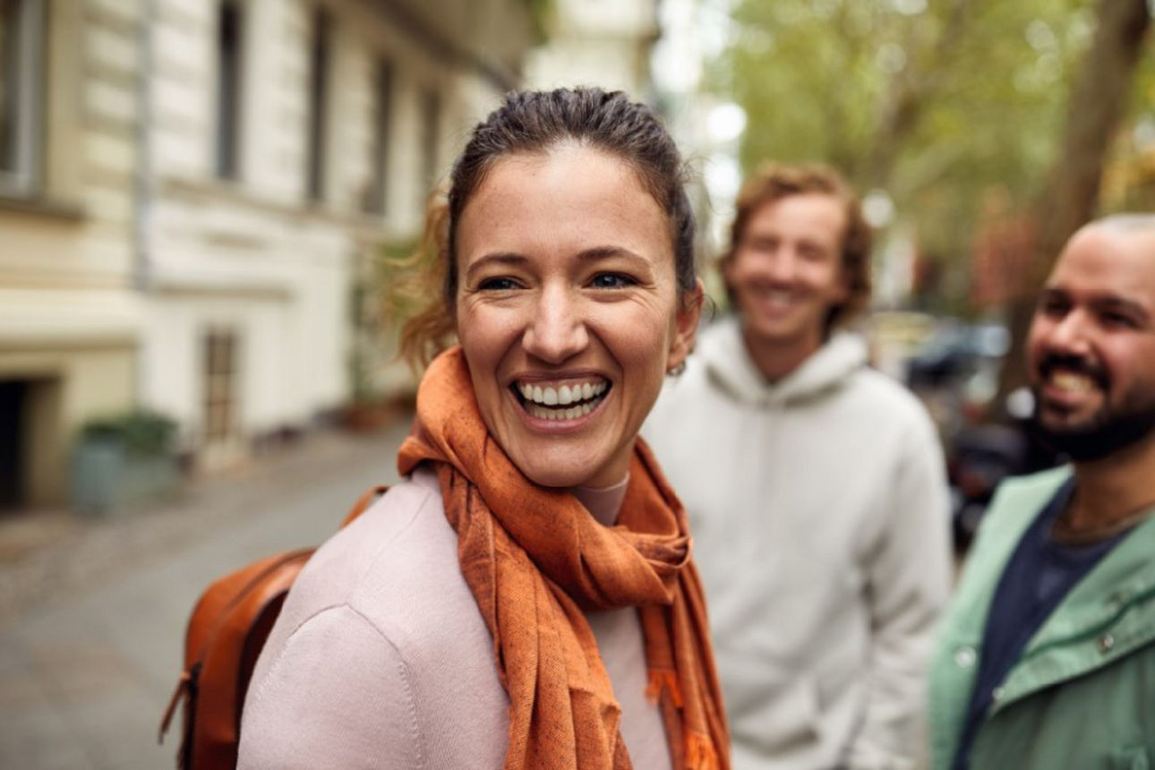 Lachende Frau mit zwei Männern auf der Straße