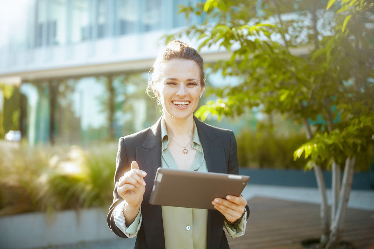 Frau hält Tablet in der Hand und lächelt.