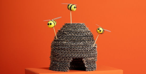 Oranger Hintergrund mit symbolisch abgebildeten Bienstock und drei Bienen.