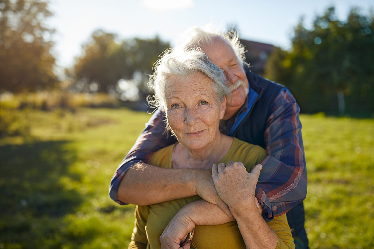 Älteres Paar umarmt sich im Freien bei sonnigem Wetter