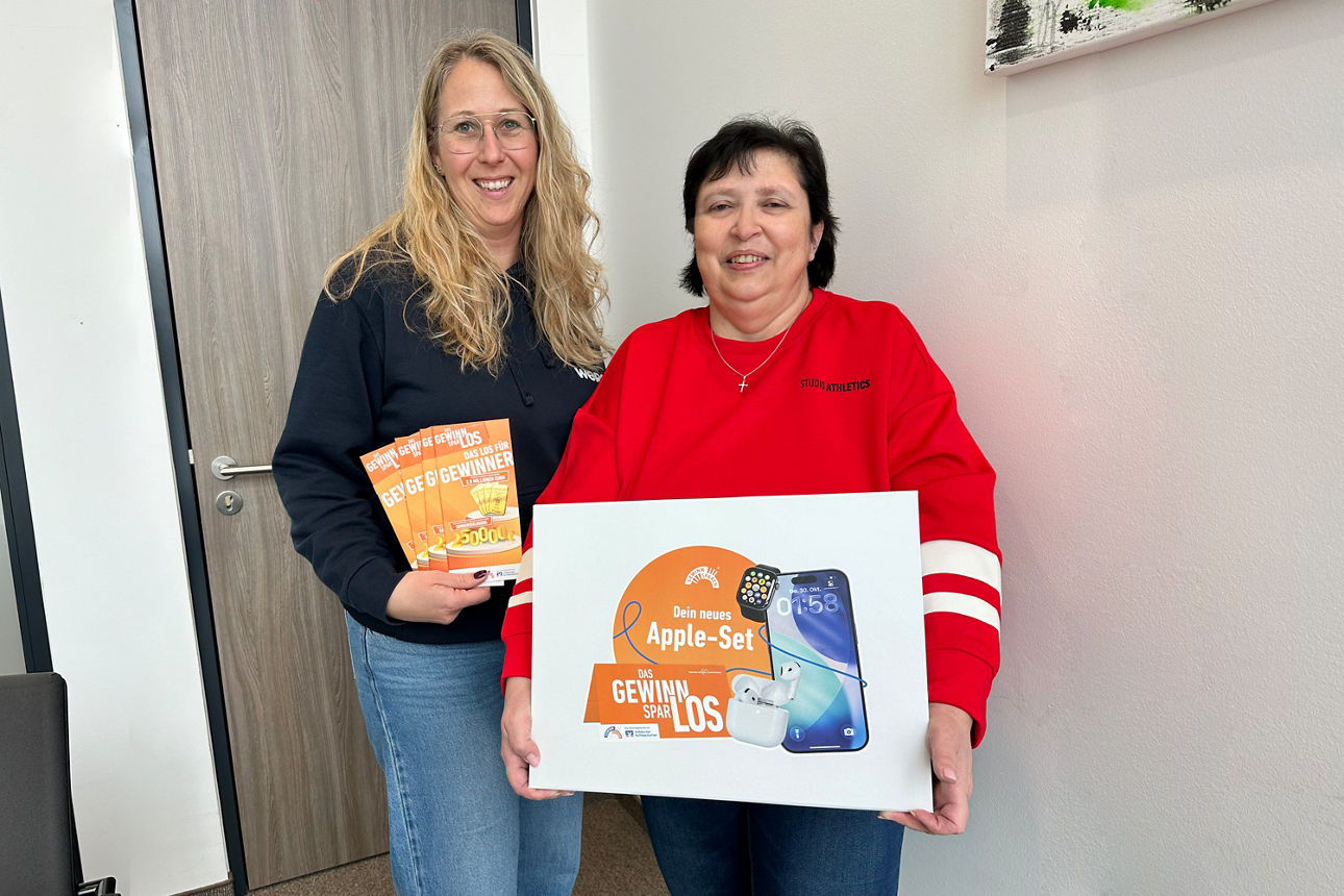 Eine Frau in einem roten Sweatshirt hält ein Plakat in der Hand, auf dem ein Apple-Gerät zu sehen ist