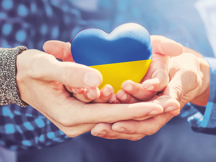Hände halten Herz mit ukrainischen Flaggenfarben