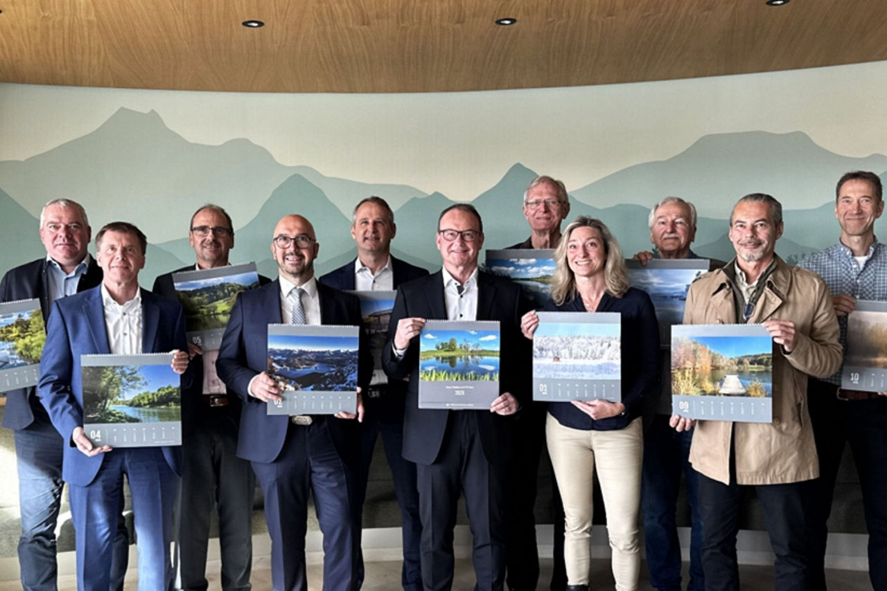 Business-Team posiert vor einer Landschaftskulisse mit hellgrünem Bergpanorama im Hintergrund.