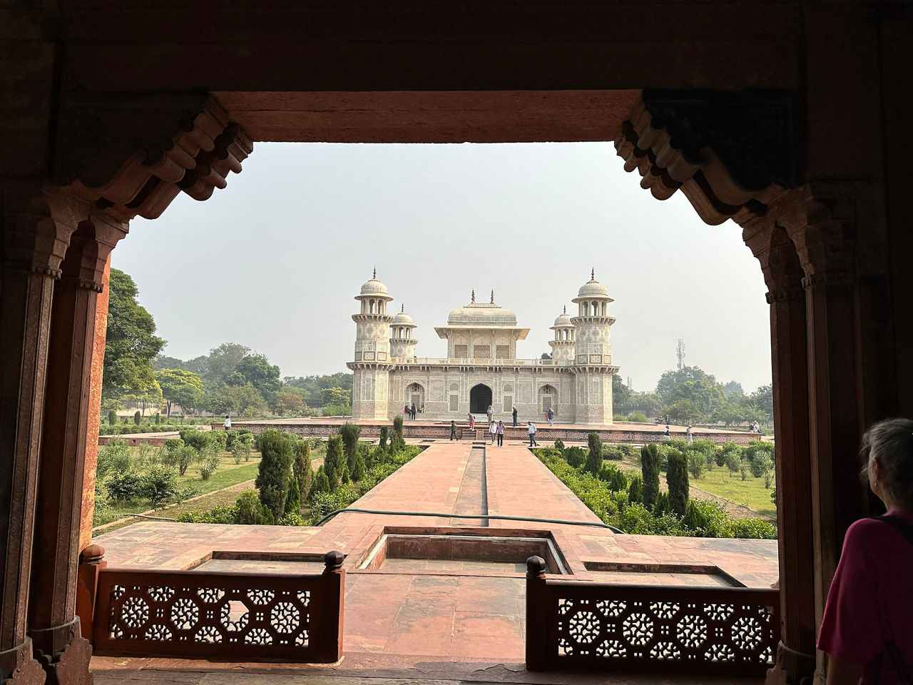 Eine Frau blickt aus einem Torbogen und beobachtet ein Gebäude in der Ferne