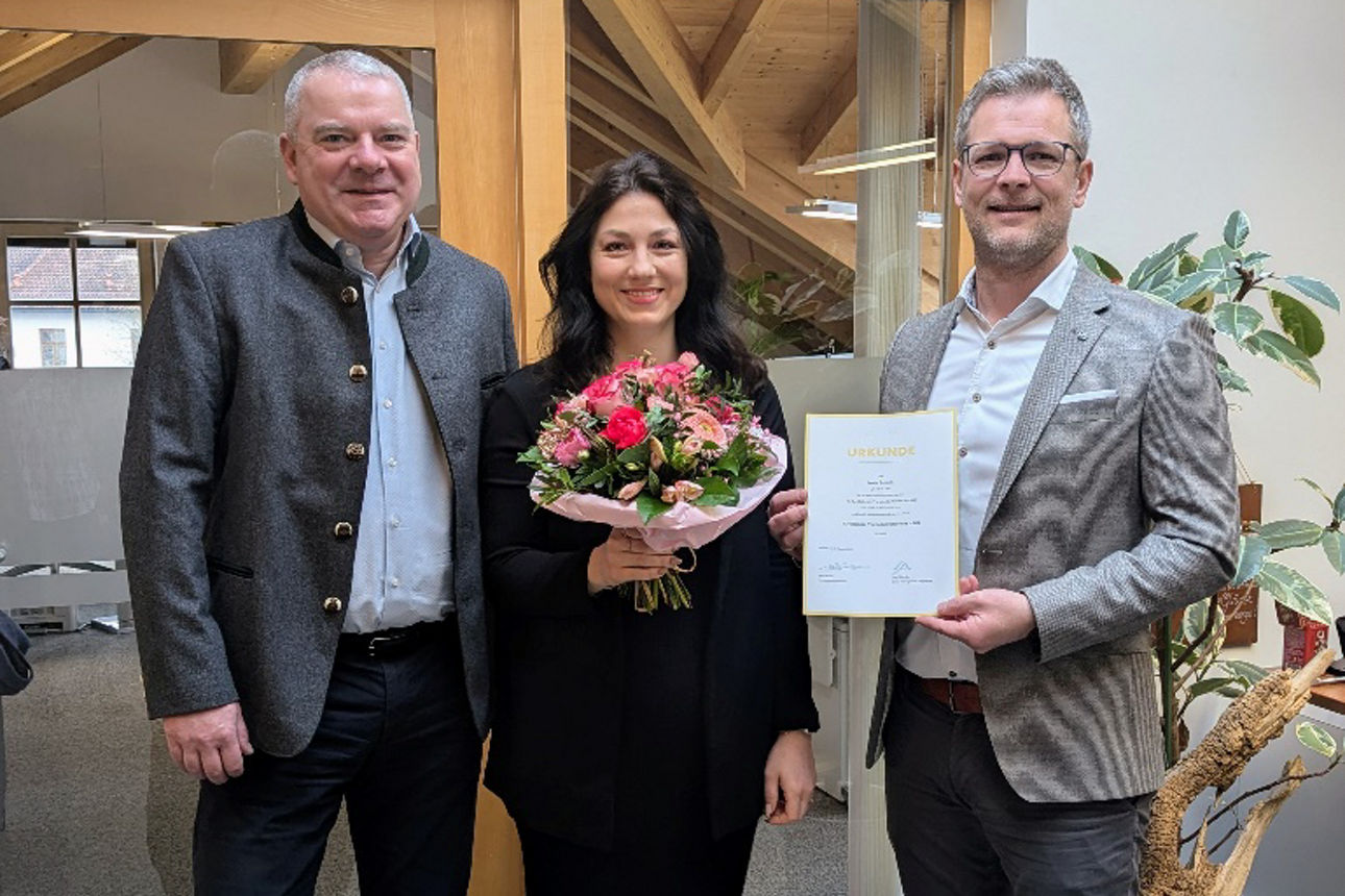 Drei Personen, mittig mit Blumenstrauß, rechts mit Zertifikat zur Vorstandsreferentin