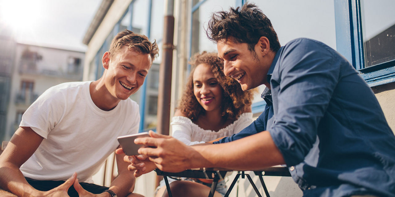 Drei Personen schauen gemeinsam auf ein Smartphone