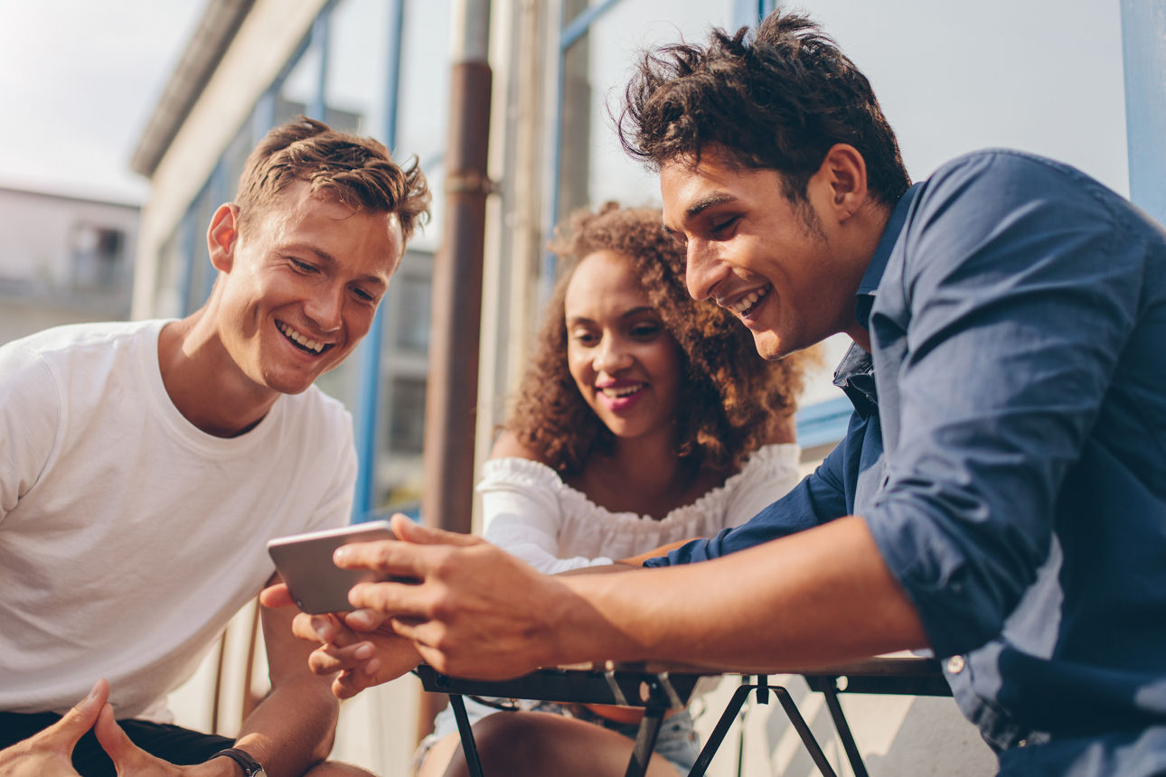 Drei Personen schauen gemeinsam auf ein Smartphone