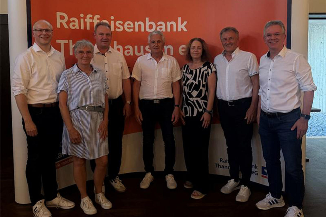 Eine Gruppe von sieben Personen, die vor einem Banner der Raiffeisenbank Thannhausen für ein Foto posieren.