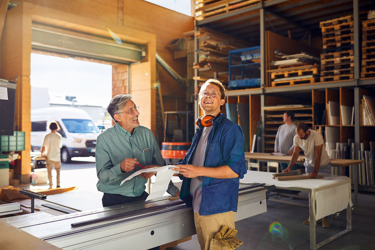 Zwei Männer stehen in einer Halle und lachen
