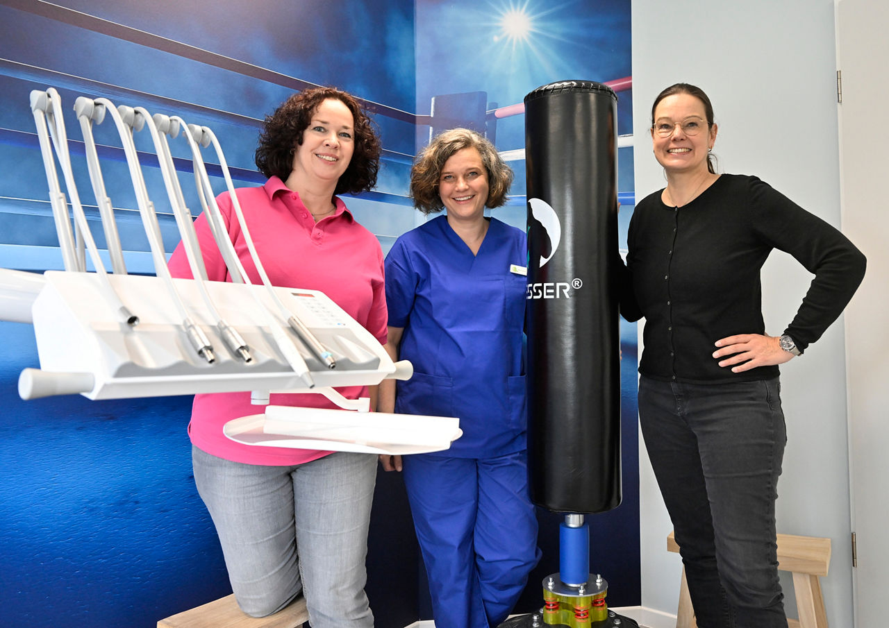 Drei Frauen stehen in einem Zahnarztpraxiszimmer
