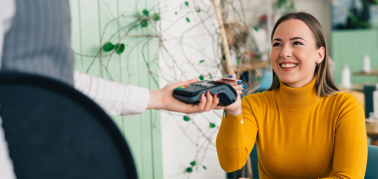 Frau hält ihr Smartphone über ein Bezahlgerät