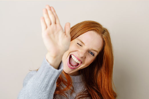 Rothaarige Frau hebt freudig die rechte Hand