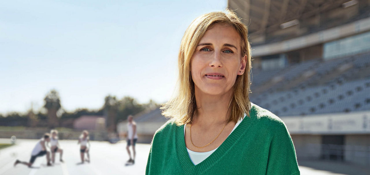 Eine Frau in Porträtaufnahme; im Hintergrund ein Sportstadium