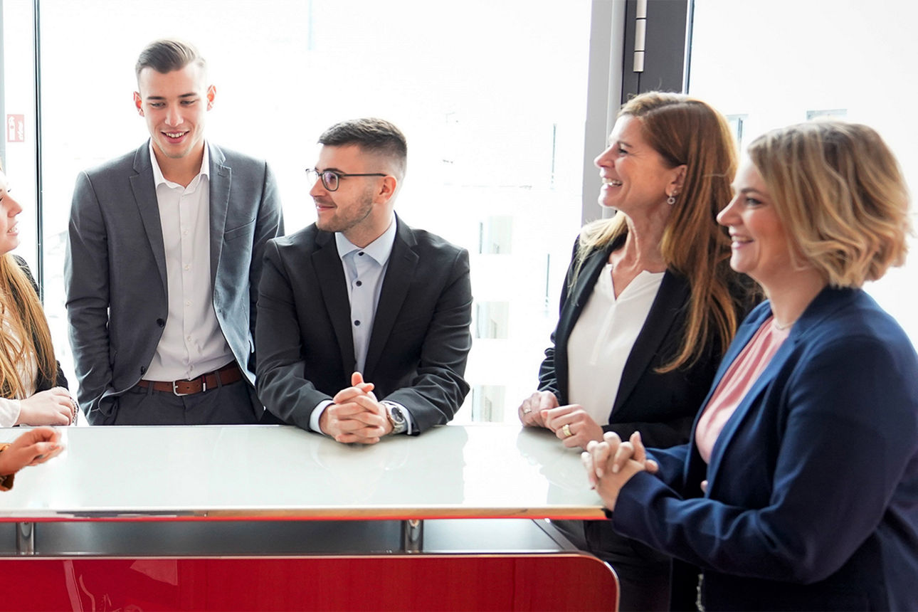 Gruppenbild von Auszubildenden und unseren Ausbilderinnen am Stehtisch