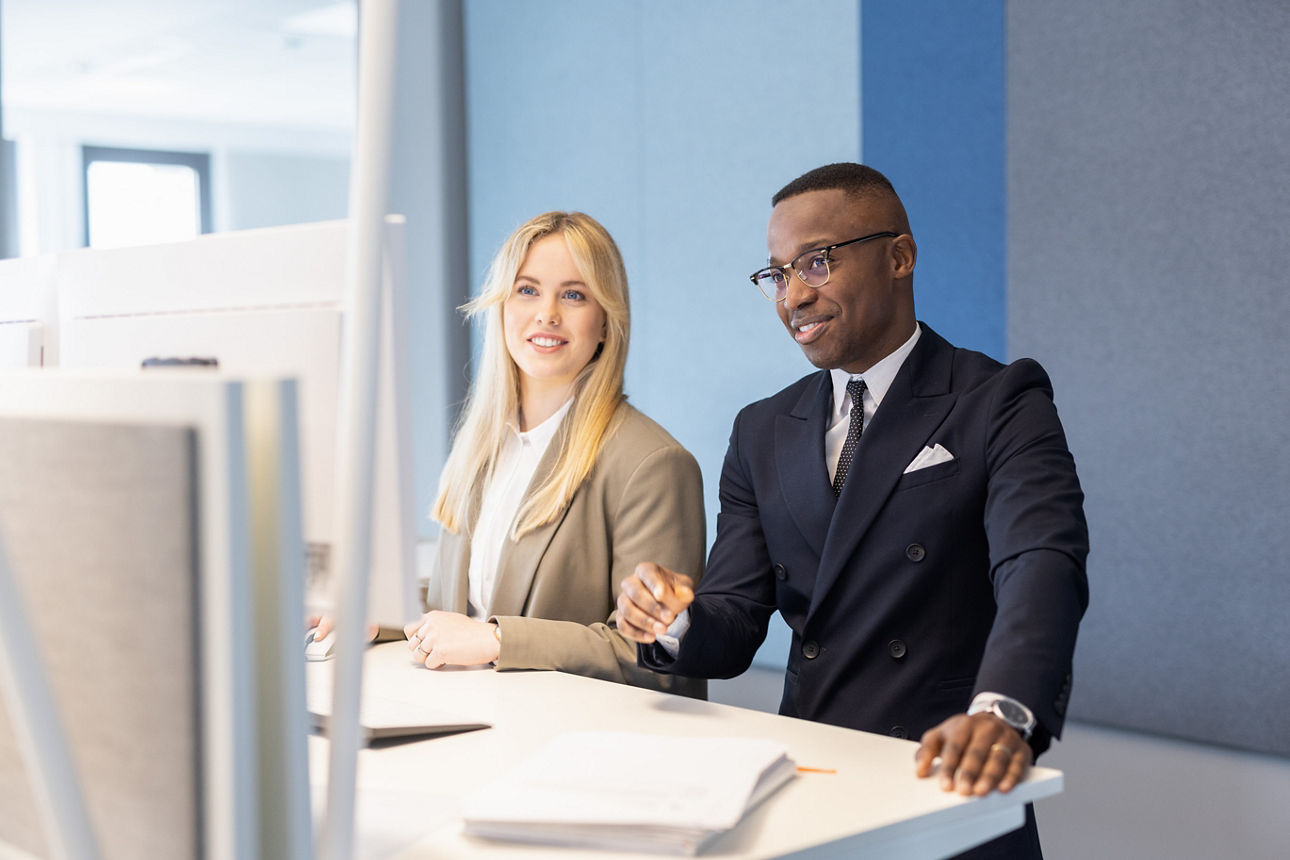 Mann sitzt lächelnd an seinem Schreibtisch in der Bank