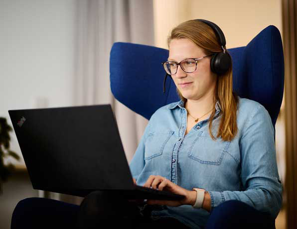 Kollegin sitzt am Laptop im blauen Sessel