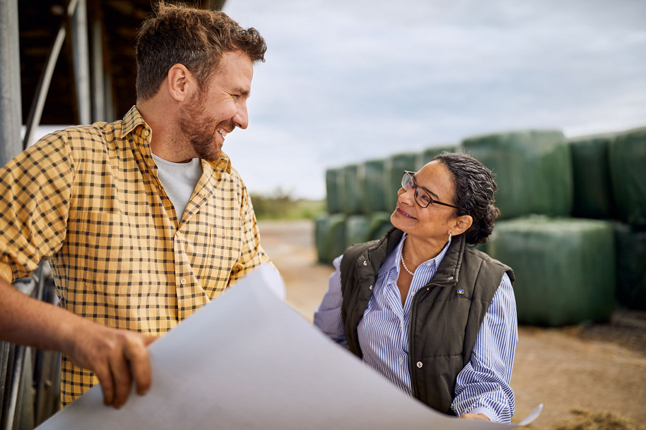 Beraterin im Gespräch mit Landwirt und einem Bauplan in der Hand