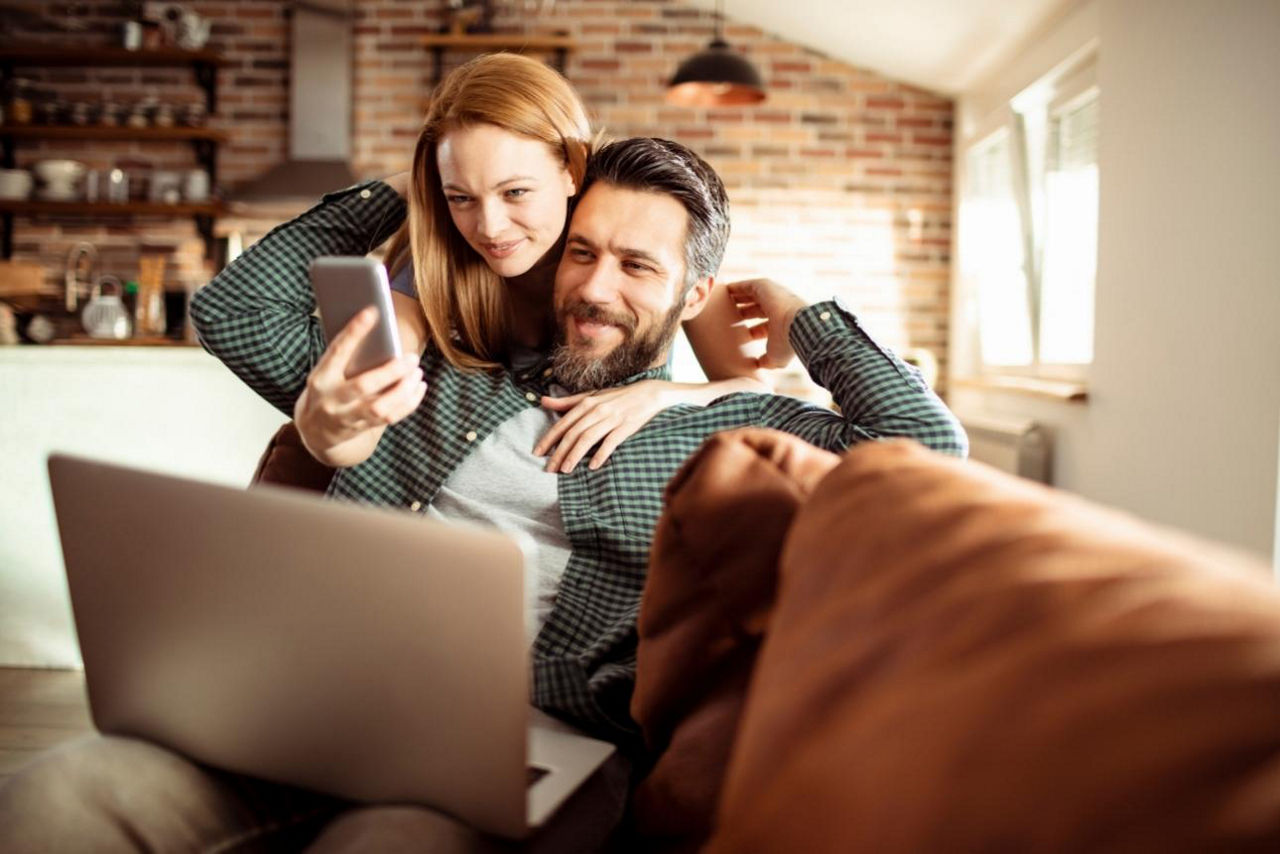 Paar sitzt auf COuch und checkt gemeinsame FInanzen