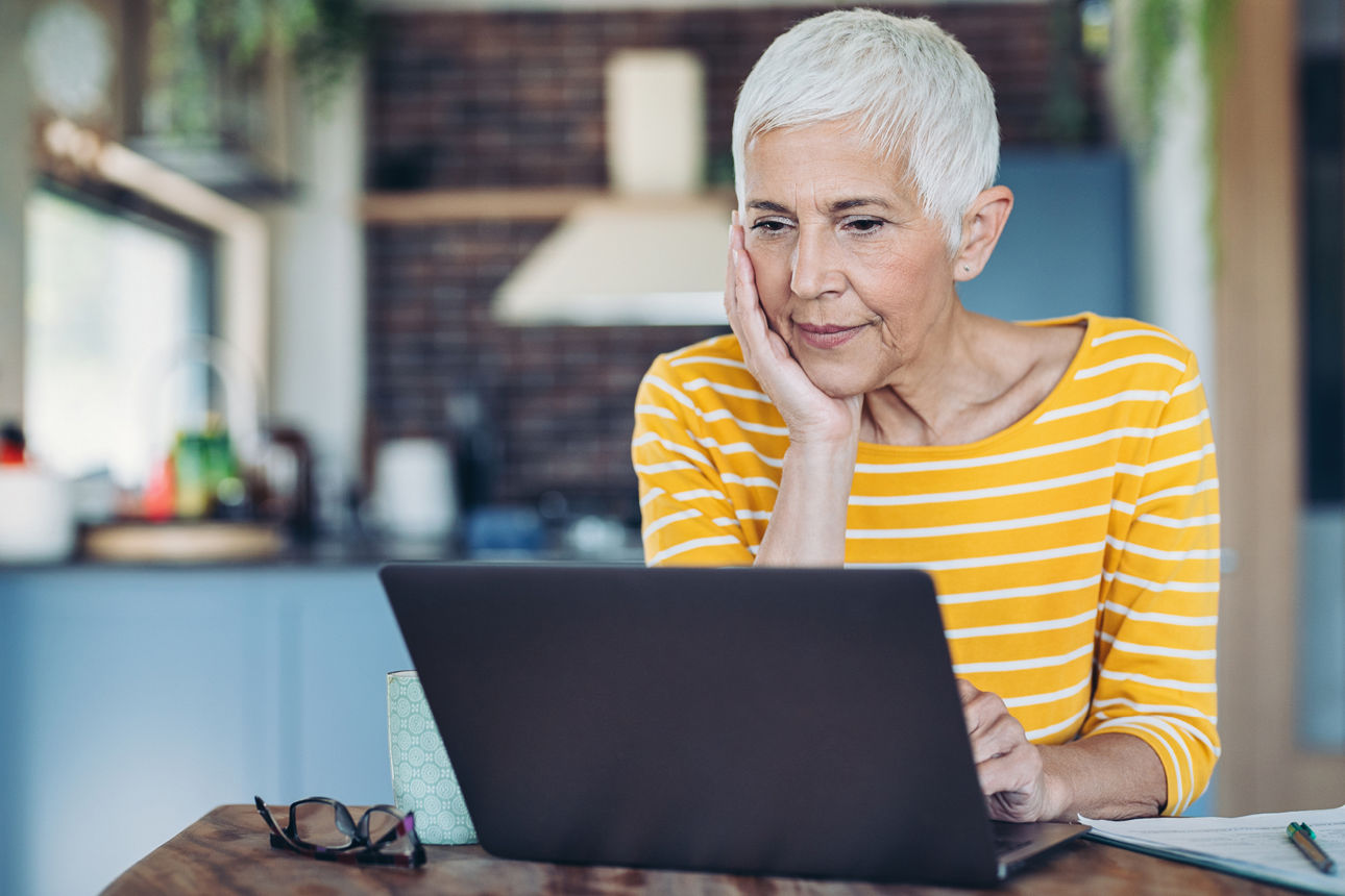 Eine Seniorin schaut auf einen Laptop