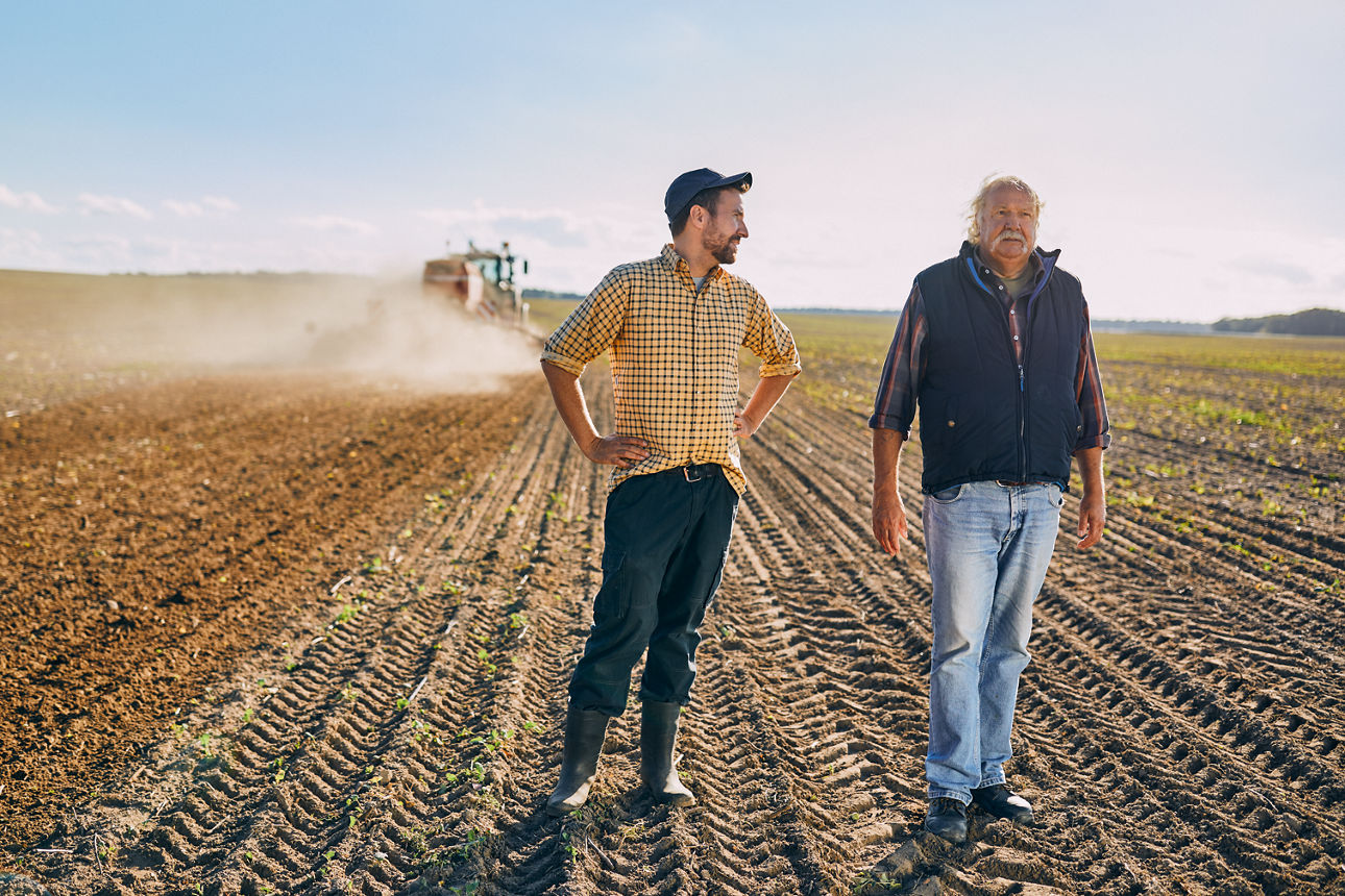 Zwei Männer stehen auf einem frisch geernteten Acker