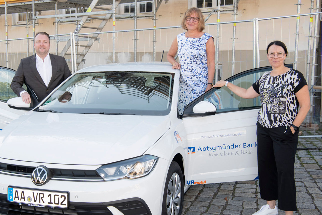 Drei Personen stehen neben einem weißen Volkswagen Polo