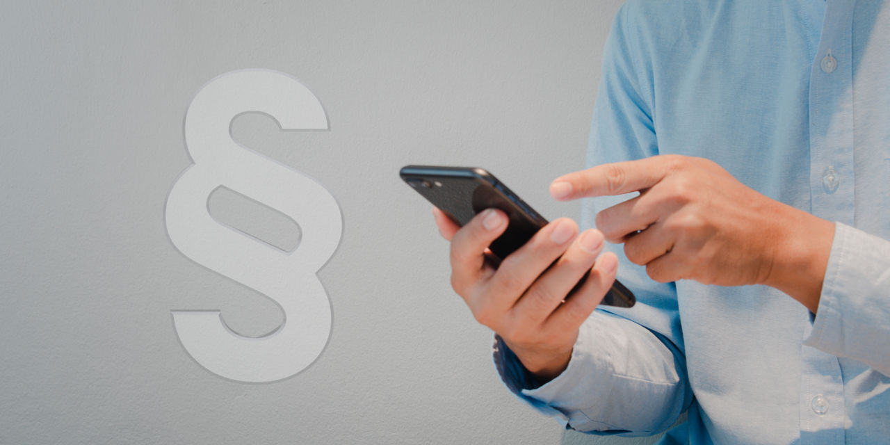 Eine Person tippt auf ein Smartphone, daneben ist ein großes Paragrafenzeichen als Symbol für Recht.