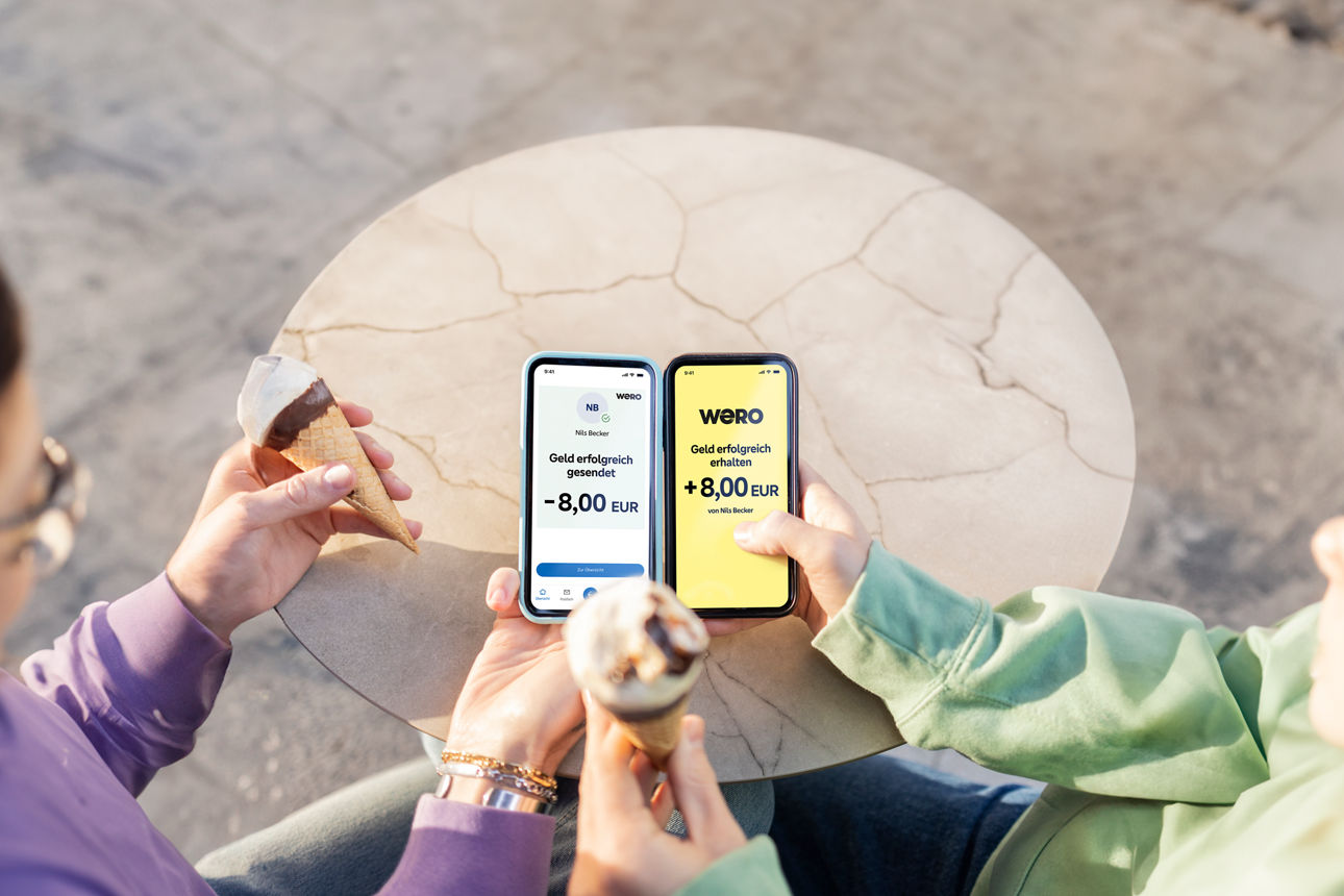 Zwei Personen teilen sich das Geld für ein Eis über WERO und halten Handys