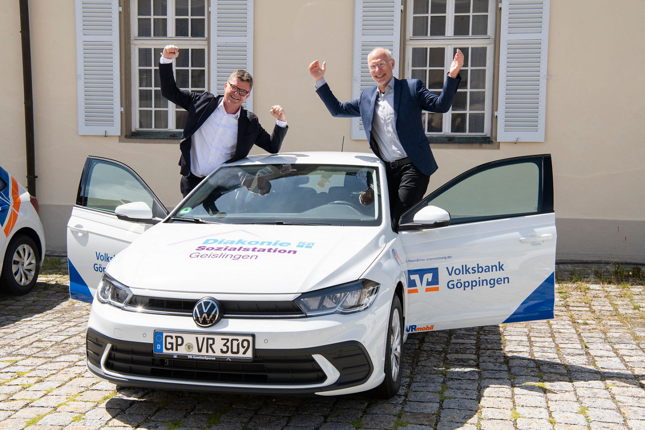 Zwei Herren jubeln neben einem Auto