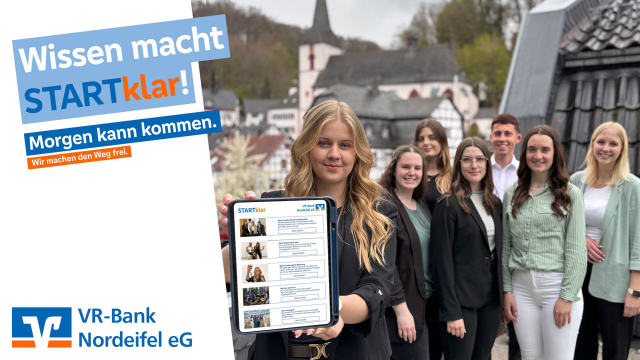 Azubis stehen zusammen wähend ein Azubi ein Tablet in die Kamera hält