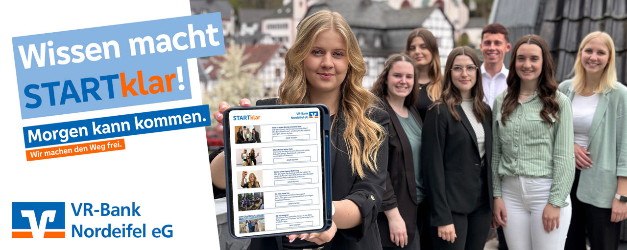 Eine Azubis steht vorne auf dem Bild und hält ein Tablet in die Kamera. Dahinter stehen ein paar andere Azubis