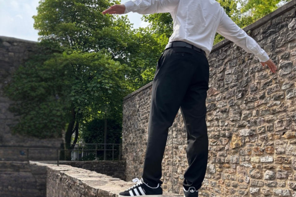 Ein Mann steht auf einer Mauer und streckt die Arme aus