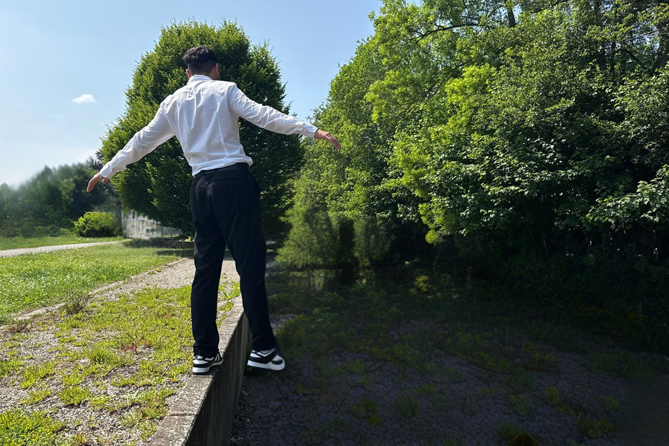 Ein Mann steht auf einer Mauer und streckt die Arme aus