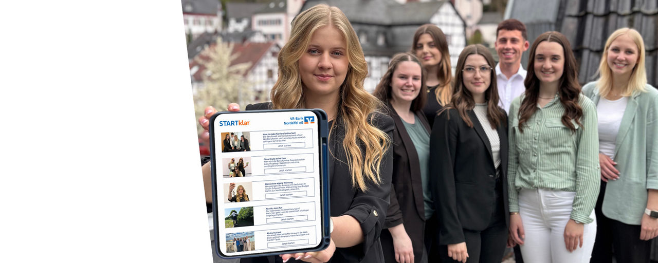 Eine Azubis steht vorne auf dem Bild und hält ein Tablet in die Kamera. Dahinter stehen ein paar andere Azubis