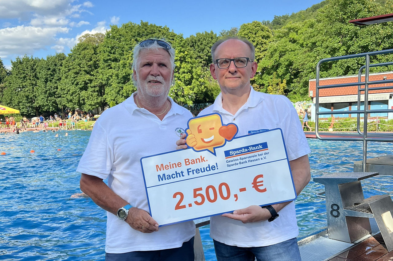 Kommunikationschef der Sparda-Bank Hessen und Vorsitzender des Schwimmbadvereins halten Spendenscheck in der Hand