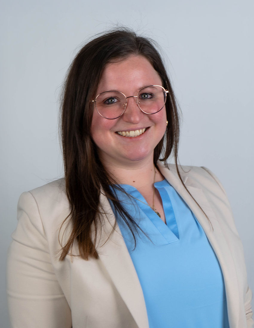 Foto unserer Vermögensberaterin Lisa Keilhofer vor einem grauen Hintergrund in einem beigen Blazer
