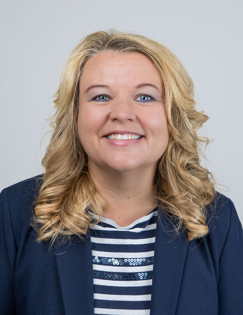 Foto unserer Kundenberaterin Marianne Klein vor einem grauen Hintergrund in einem blauen Blazer