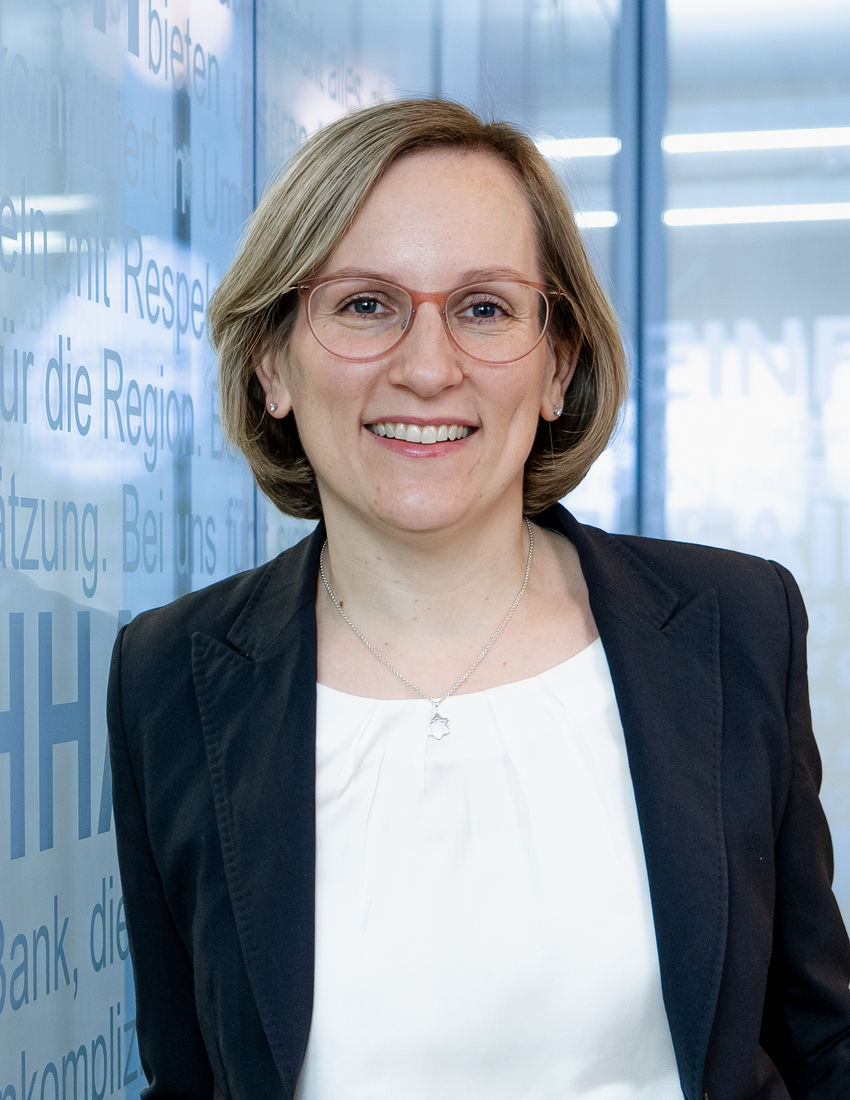 Foto unserer Vermögensberaterin Annika Scherm vor einer Büroglaswand in einem schwarzen Balzer