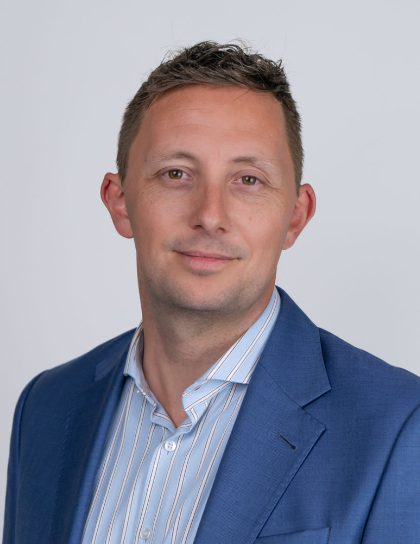 Foto unseres Kundenberaters Daniel Zottmann vor einem grauen Hintergrund in einem blauen Sakko
