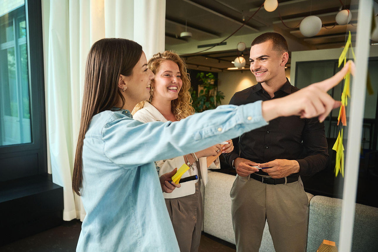 Vier junge Leute sitzen zusammen und blicken lächelnd in die Kamera