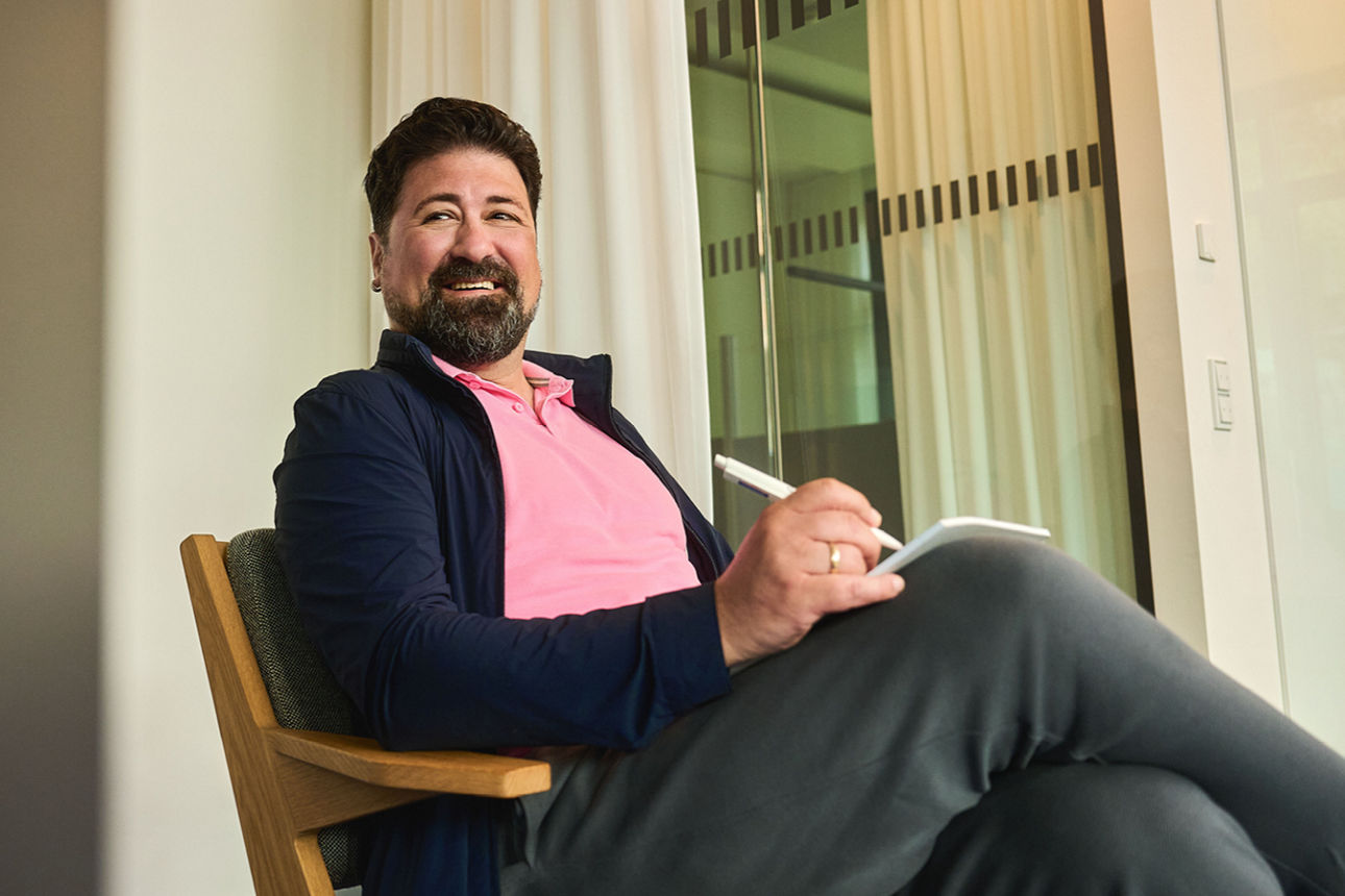 Ein Mann sitzt im Stuhl und notiert sich etwas.